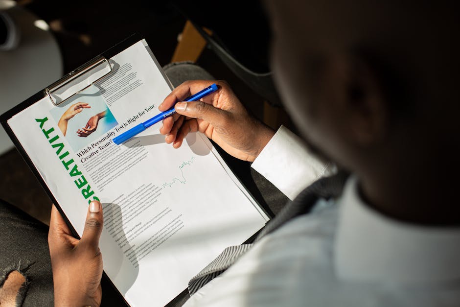 A person in a suit analyzing a document about creativity on a clipboard, using a blue pen.